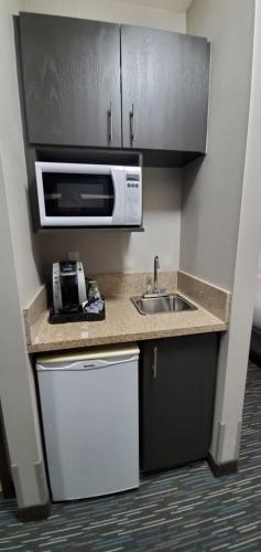 a small kitchen with a sink and a microwave at Wingate by Wyndham Lethbridge in Lethbridge