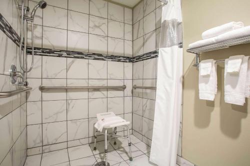 a white tiled bathroom with a shower and a stool at Travelodge by Wyndham Wahpeton in Wahpeton