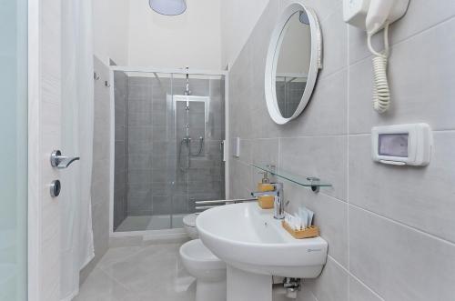 a white bathroom with a sink and a shower at Blunotte Torino - Piazza Castello in Turin