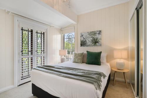 a white bedroom with a large bed with green pillows at Contemporary Cottage in Perfect Lifestyle Address in Brisbane