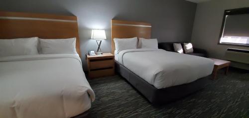 a hotel room with two beds and a chair at Wingate by Wyndham Lethbridge in Lethbridge