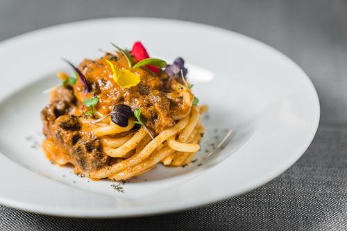 a white plate of pasta on a table at LHP Hotel River & SPA in Florence