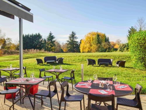 a group of tables and chairs in a field at Novotel Senart Golf De Greenparc in Saint-Pierre-du-Perray