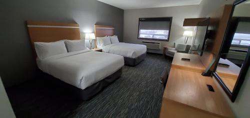 a hotel room with two beds and a television at Wingate by Wyndham Lethbridge in Lethbridge