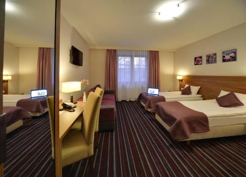 a hotel room with two beds and a desk at Hotel Camelot in Szczawno-Zdrój