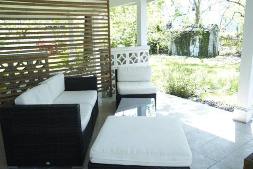 a porch with a white couch and two chairs at Rainbow House and small garden in Princeton