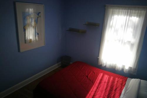 a bedroom with a red bed and a window at Rainbow House and small garden in Princeton