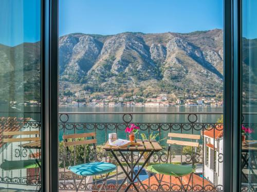 uma varanda com mesa e cadeiras e vista para as montanhas em Apartments Windrose em Kotor