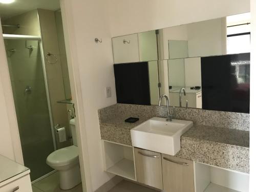 een badkamer met een wastafel, een toilet en een spiegel bij Flat Beira-Mar Landscape in Fortaleza