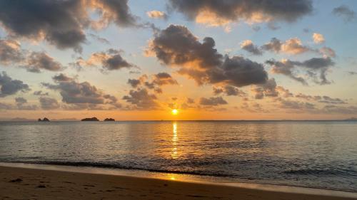a sunset on the beach with the sun setting at Sean Sabai Home e Ristobar in Taling Ngam Beach