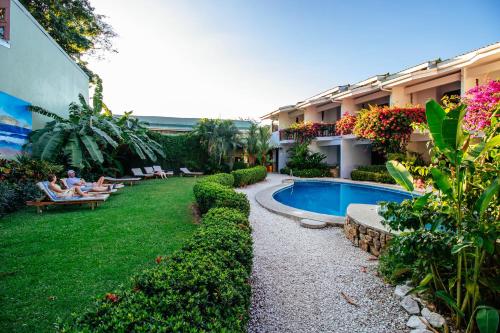 a hotel yard with a pool and people sitting on chairs at Hotel Giada in Sámara