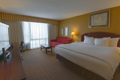 a hotel room with a large bed and a red chair at MCM Elegante Hotel & Suites Lubbock in Lubbock
