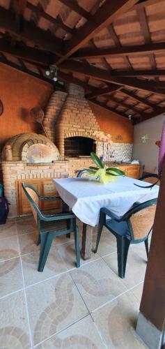 uma mesa e cadeiras num quarto com um forno de tijolo em Suítes no paraíso da Ilhabela em Ilhabela