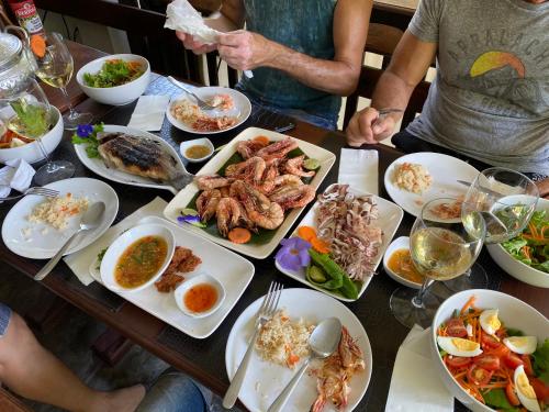 a table with plates of food and people sitting around it at Sean Sabai Home e Ristobar in Taling Ngam Beach
