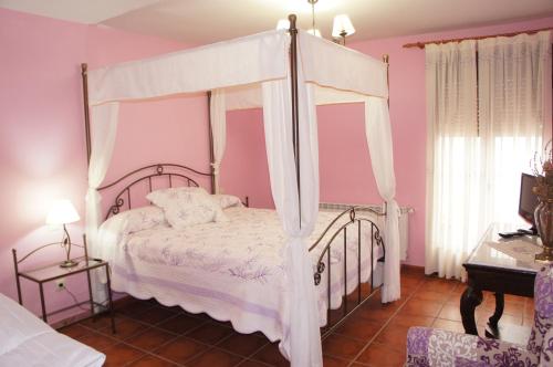 a bedroom with a canopy bed with pink walls at Casa Rural Blas in Brihuega