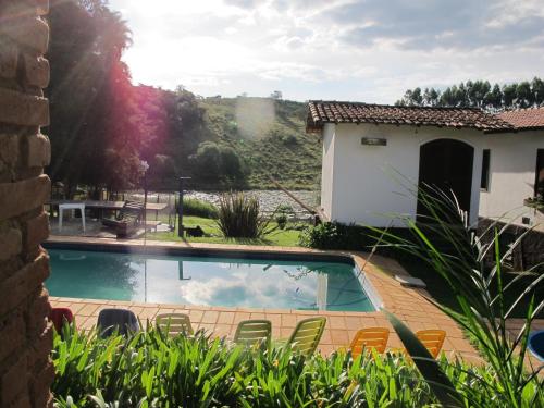 a swimming pool with chairs and a house at Arte de Minas in São Gonçalo do Sapucaí