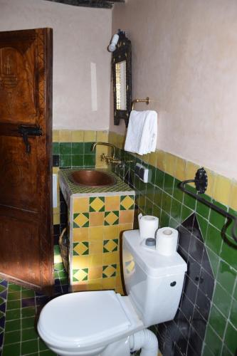 a bathroom with a toilet and a green and yellow tiles at Kasbah Assafar in Kalaat MGouna