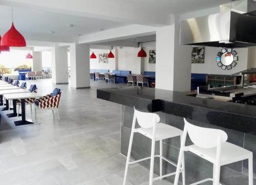 a restaurant with a bar with white chairs and tables at Decameron La Marina Guayabitos, Ramada All-Inclusive Resort in Rincon de Guayabitos
