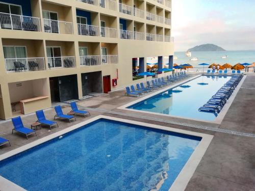 a view of the pool at a resort with chairs and the ocean at Decameron La Marina Guayabitos, Ramada All-Inclusive Resort in Rincon de Guayabitos