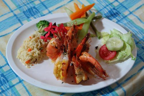 a white plate of food with shrimp rice and vegetables at Hotel Miraflores in El Cuco