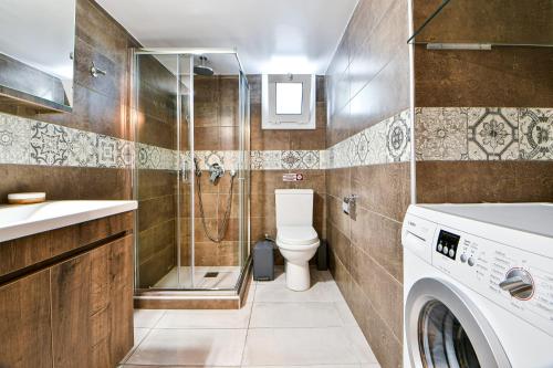 y baño con ducha, aseo y lavadora. en Koukounari Luxury Apartments, en Vathí