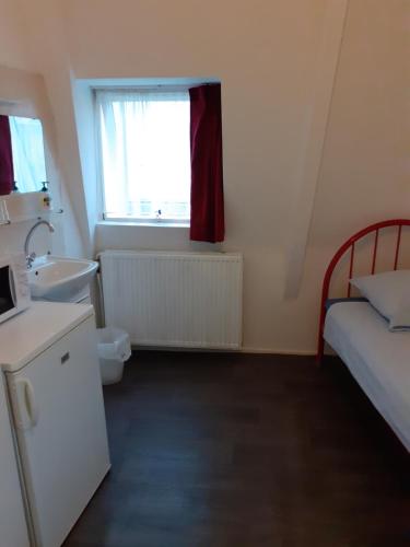 een kleine badkamer met een bed en een wastafel bij Hostel Pension Tivoli in Groningen