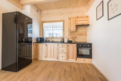 a kitchen with wooden cabinets and a black refrigerator at Farmerska Chata in Czarna Góra