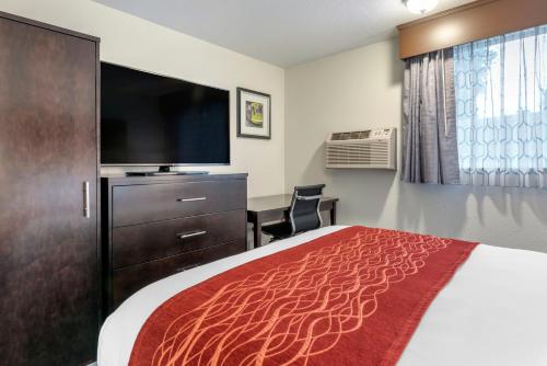 a hotel room with a bed and a flat screen tv at Comfort Inn & Suites Tigard near Washington Square in Tigard