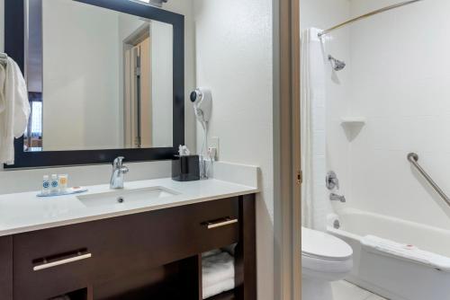 a bathroom with a sink and a toilet and a mirror at Comfort Inn & Suites Tigard near Washington Square in Tigard