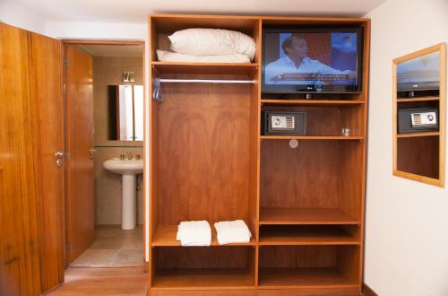 a room with a tv and a closet with a bathroom at Hotel Premier Bariloche in San Carlos de Bariloche