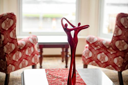 a red vase sitting on a table with two chairs at Inglewood - OPUL EXPRESS in Douglas