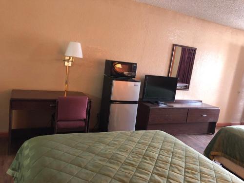 CiscoにあるLone Star Innのベッド、デスク、テレビが備わるホテルルームです。