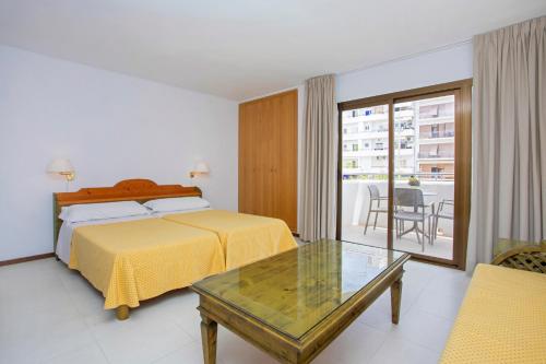 a hotel room with a bed and a table at Apartamentos Bon Lloc in Santa Eularia des Riu
