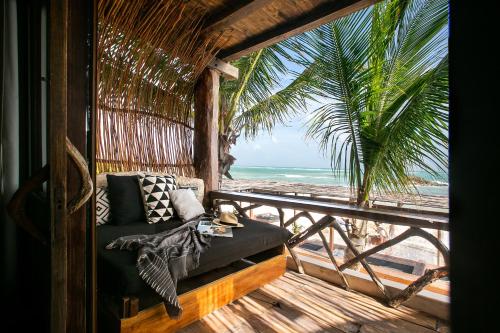 a bed on a porch with a view of the beach at Amansala Resort in Tulum