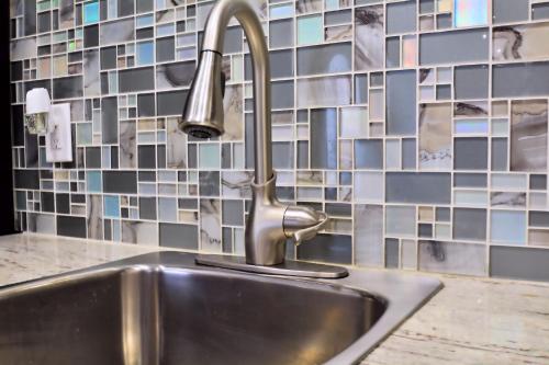 a sink in a kitchen with a tiled wall at Crystal Lodge Motel in Ventura