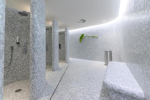a white bathroom with a shower and a sink at Hotel Caroline in Vienna