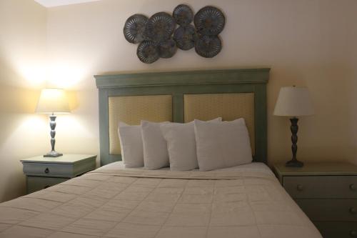 um quarto com uma cama com almofadas brancas e 2 candeeiros em The Prytania Park Hotel em Nova Orleans