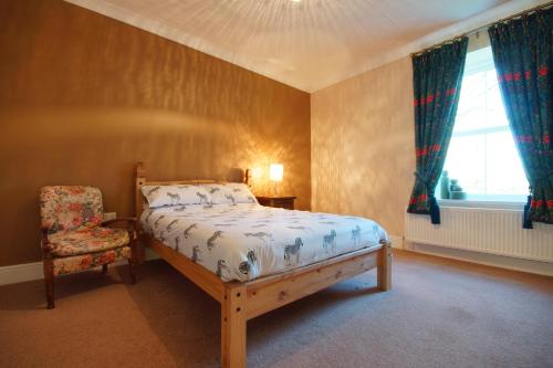 a bedroom with a bed and a chair and a window at Paull Holme Farm Bed and Breakfast in Paull