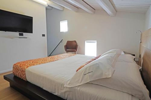 a bedroom with a bed with a chair and a flat screen tv at neropece in Ragusa