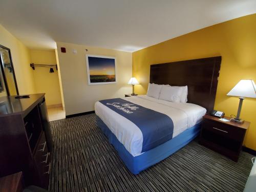 a hotel room with a large bed and a television at Days Inn by Wyndham Atlanta/Southlake/Morrow in Morrow