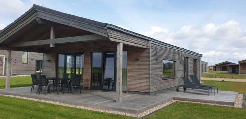 a small cabin with a deck with a table and chairs at Gud Jard Lodge Nr 08 - Design-Ferienhaus mit exklusiver Ausstattung in Pellworm