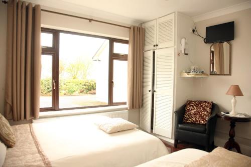 a bedroom with two beds and a window and a chair at Torine House B&B in Killorglin