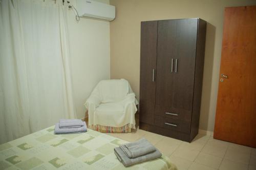 a bedroom with a bed and a chair and a cabinet at CÓMODO DEPARTAMENTO EN ZONA CÉNTRICA in Rafaela