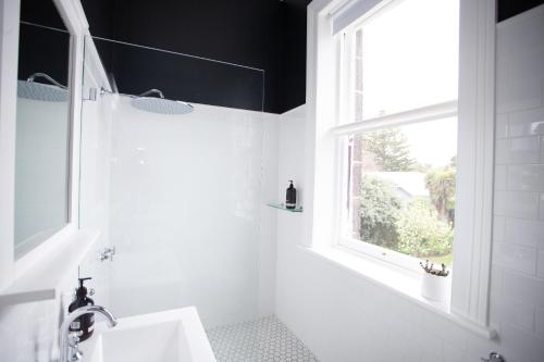 a white bathroom with a window and a sink at Old Market Inn in Port Fairy