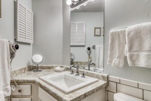 Baño blanco con lavabo y espejo en Plantation West Resort en Gulf Shores