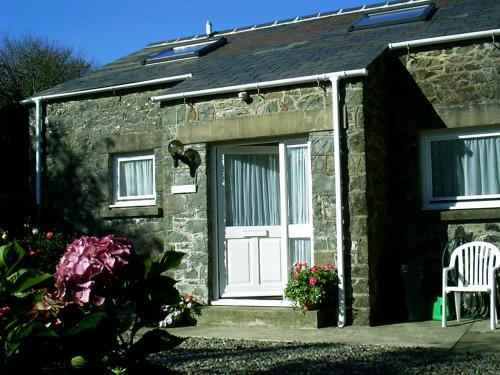 a stone house with a white door and a chair at Ty r Pwmp in Haverfordwest