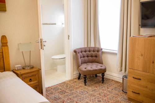 a bedroom with a chair next to a toilet at Inglewood - OPUL EXPRESS in Douglas