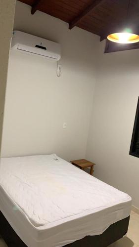 a white bed in a room with a white wall at Loft Pireneus 1 in Pirenópolis