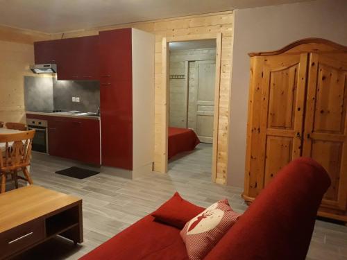 a living room with a red couch and a kitchen at Chalet TERRA LOUP in Le Dévoluy