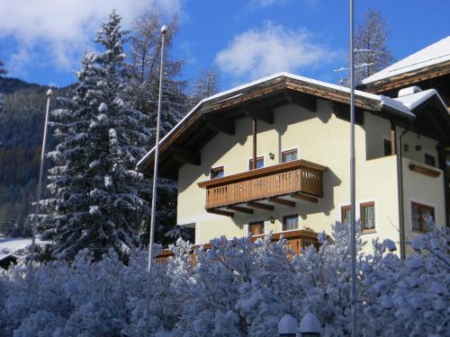 a building with a wooden balcony in the snow at Appartamenti Riz Claudio in Campitello di Fassa